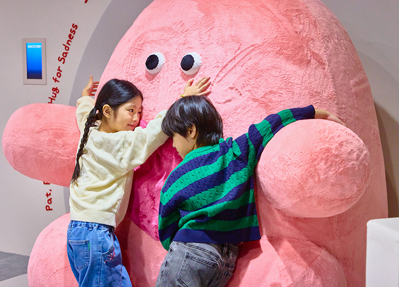 마음이궁금해 전시실에서 분홍색 큰 인형을 안고있는 어린이들 사진